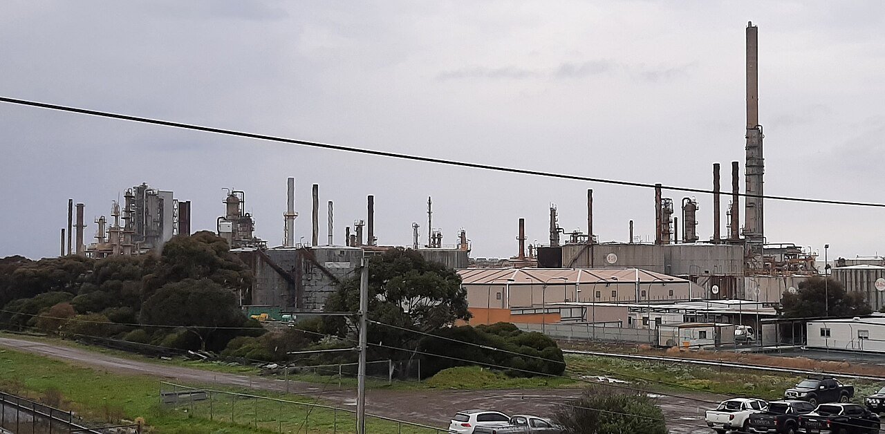 Refinery process area with interconnecting piping and structures — live leak sealing crews work inside operating units under permit control