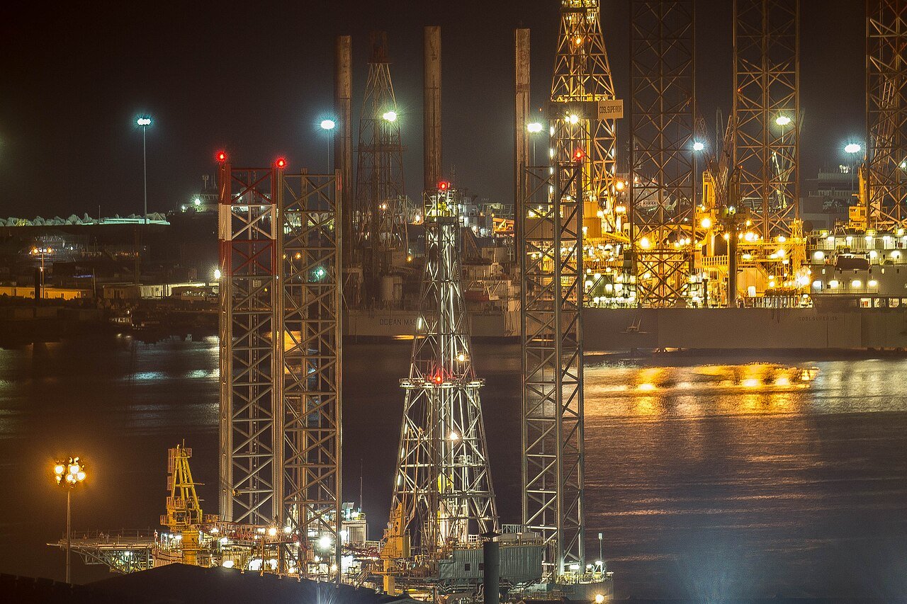 Night view of a large industrial port and drydock area with cranes and vessels, illustrating barge and sea freight logistics for remote leak repair